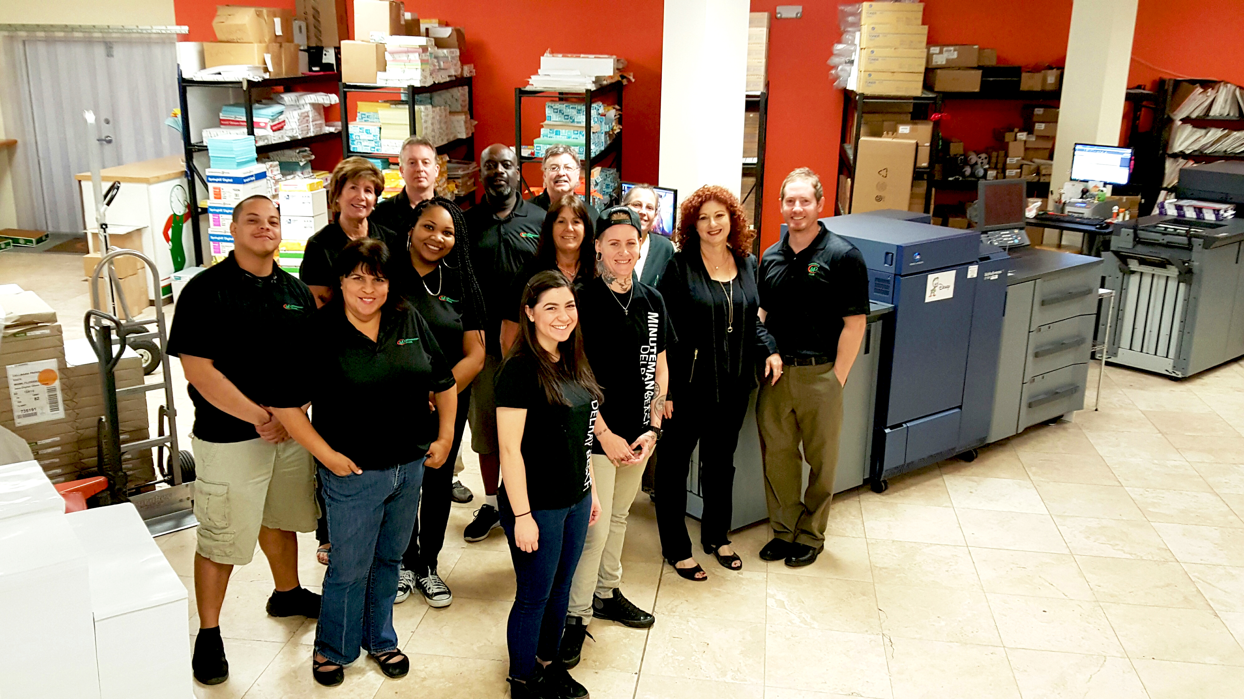 The Minuteman Press franchise staff in Delray Beach love their two Konica Minolta bizhub PRESS® 1100s. Pictured from left to right are: Josh, Idie, Julie, Shennel, Angelo, Melissa, Reggie, Carmen, James, Ricky, Linda, Gail, and owner Matthew Perry.